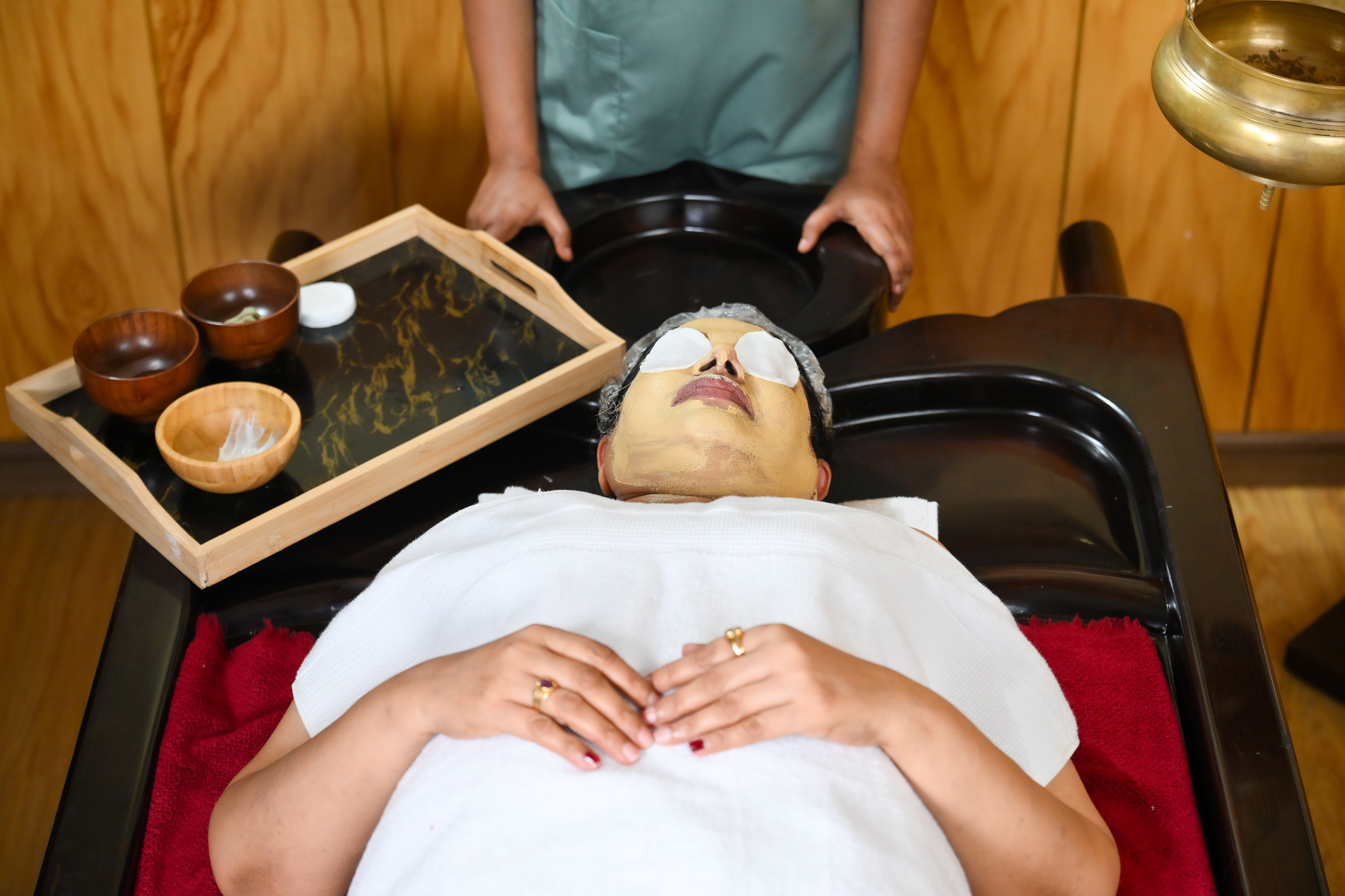 Woman receiving an Ayurvedic herbal facial treatment at Dhanwanthari Ayurveda Dubai